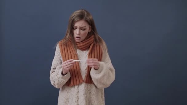 Sick girl wrapped in a warm scarf measures the temperature - Materiaali, video