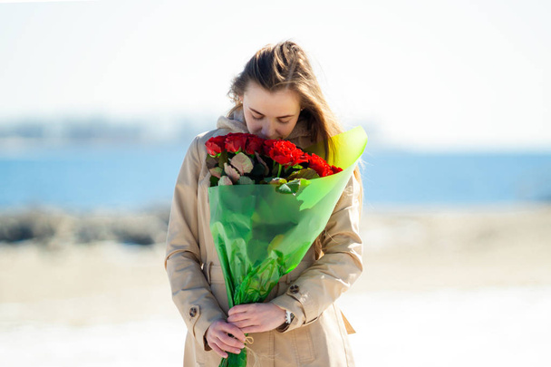 Młoda kobieta lubi zapach bukietu róż.  - Zdjęcie, obraz