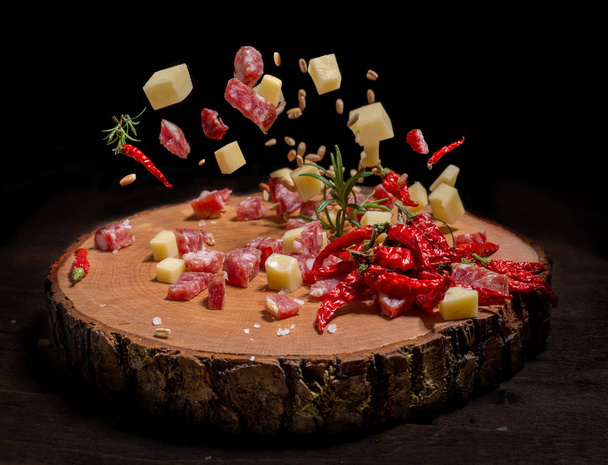 kuutioiksi leikattu salami ja juusto kulhoon puinen levy
 - Valokuva, kuva