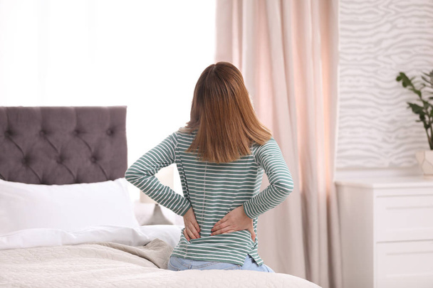 Young woman suffering from back pain at home - Foto, afbeelding