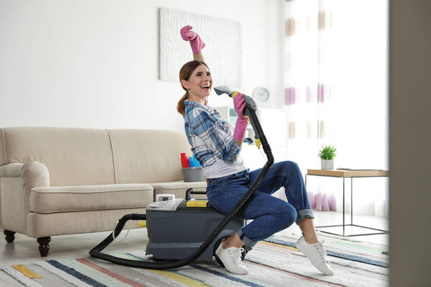 Happy woman having fun while cleaning room - 写真・画像