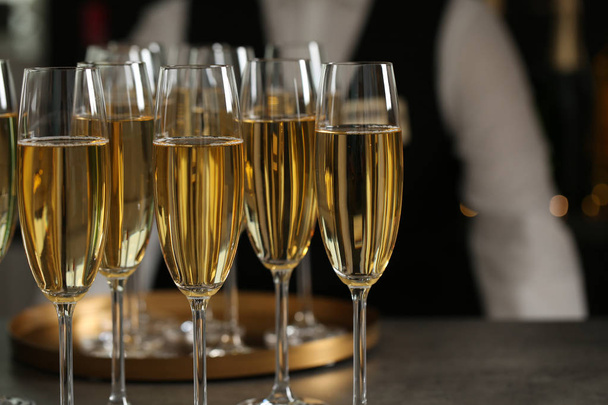 Glasses of champagne and waiter in restaurant, closeup - Photo, image
