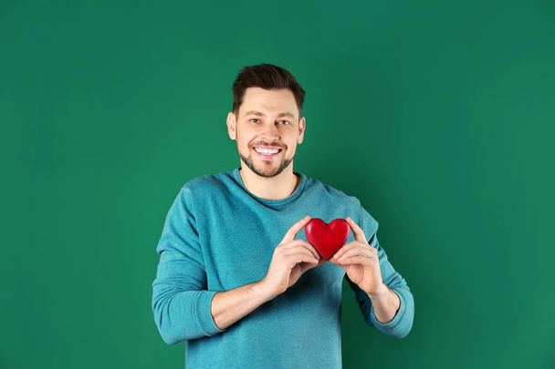Man holding decorative heart on color background - Zdjęcie, obraz
