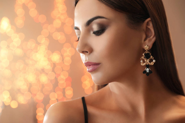 Beautiful young woman with elegant jewelry against defocused lights. Space for text - Fotoğraf, Görsel