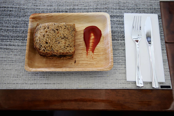 Vollkornbrot-Sandwich auf Schaumtablett und Tomatensauce mit Messern und Plastikgabeln zum Servieren im Privatjet - Foto, Bild