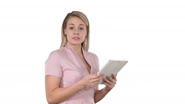 Beautiful woman using a digital tablet and talking to the camera on white background. - Filmati, video