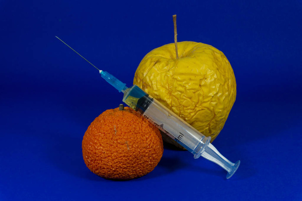 Arancione appassito e mela con ago ipodermico
 - Foto, immagini