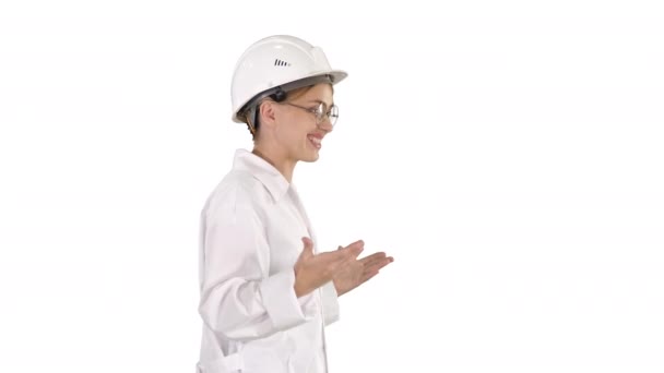 Young scientist in lab coat and hardhat walking and saying something on white background. - Кадри, відео