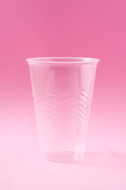 Disposable waste plastic glass on pink background.  - Foto, imagen