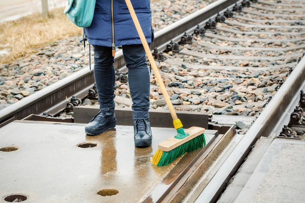 Woman railway employee clean with brush railway crossing - Photo, Image