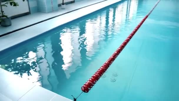 Moderní krytý bazén s modrou vodou a zdmi, pohled na plavecké stezky - Záběry, video