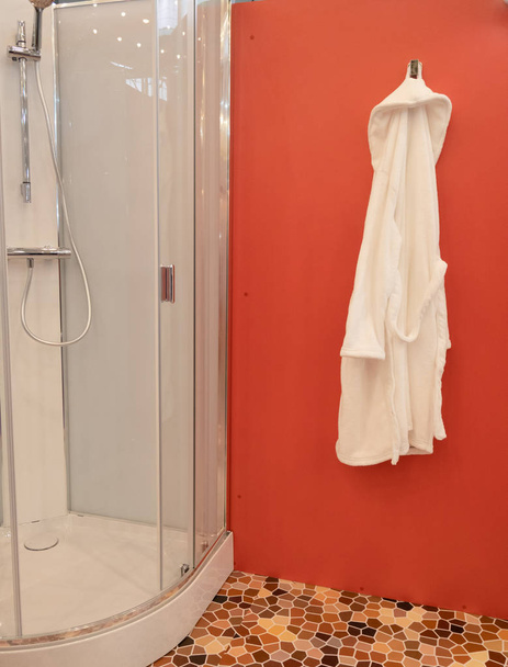 shower cabin at wellness spa center with white bathrobe hanging on red wall - Photo, Image
