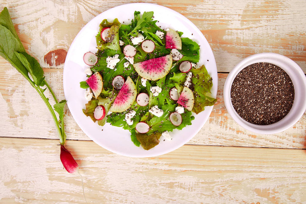 Verse watermeloen radijs salade met rucola feta, Chia op houten achtergrond. Veganistisch, vegetarisch, schoon eten, dieet, Food concept. Bovenaanzicht, vlakke lay, kopieer ruimte - Foto, afbeelding