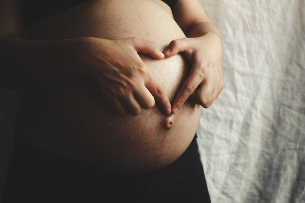 Έγκυος γυναίκα στο 9ο μήνα δείχνει την καρδιά με τα χέρια - Φωτογραφία, εικόνα