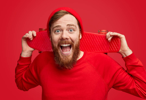 Excited hipster with red skateboard - Zdjęcie, obraz