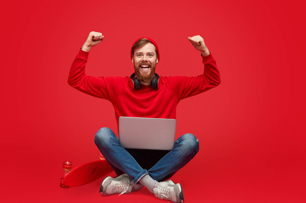 Stylish coder with laptop celebrating success - Фото, изображение