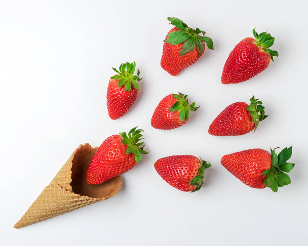 Ice cream cone with strawberries on white background. Minimal summer concept. - Фото, изображение