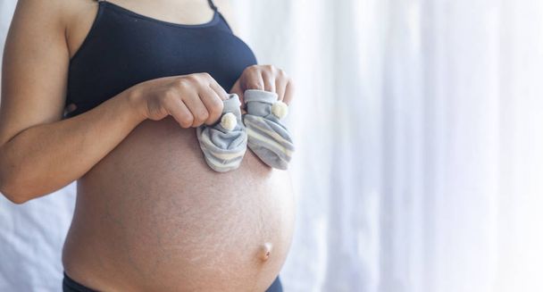 вагітна жінка з дитячим взуттям
 - Фото, зображення