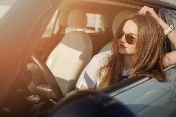 Girl posing in the car. Young girl in sport car with black sunglasses. - Фото, изображение