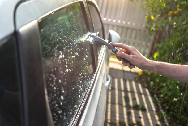 worker washing the car window with a scraper - Foto, Imagen