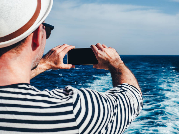 Fashionable man holding a mobile phone on the deck - Photo, image