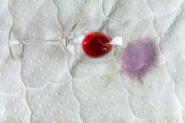 verschüttetes Weinglas auf dem Bett. versehentlich Weinglas fallen gelassen - Foto, Bild