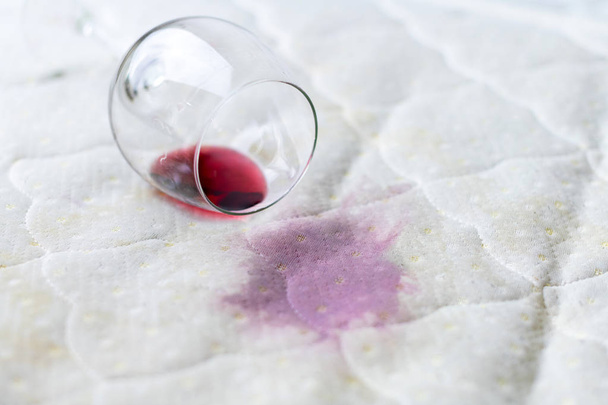 Gemorst wijn glas op het bed. Per ongeluk verloren Wineglass op - Foto, afbeelding