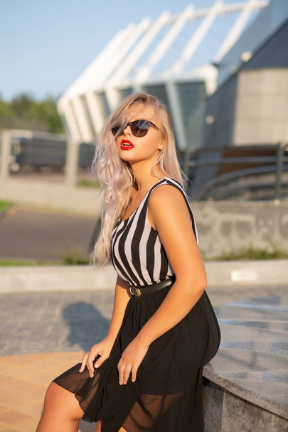 Прекрасна блондинка в окулярах і модна сукня позує на t
 - Фото, зображення