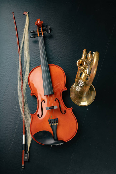 A new shining violin and an old trumpet on a dark table. Musical - Photo, Image