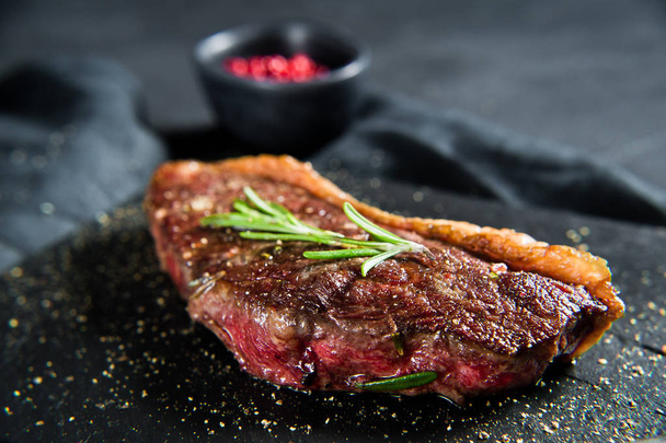 Beef ramp steak with rosemary. Black background, top view. - Фото, зображення
