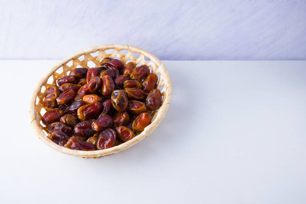 Dried dates on white background. Holy month of Ramadan, concept. Righteous Muslim lifestyle. Starvation. Dates in wooden basket. Vegetarian food. Copy space - Valokuva, kuva