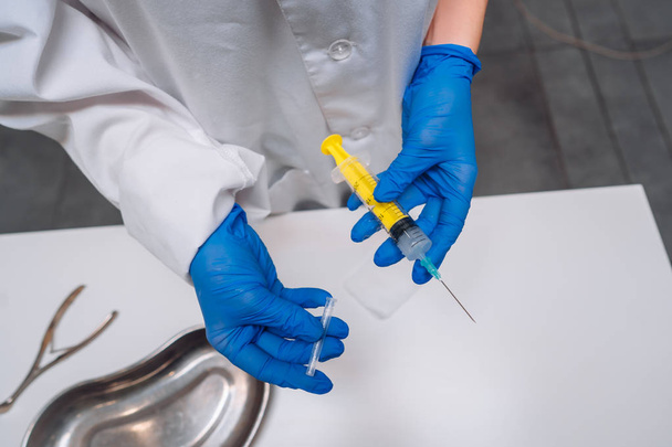 Les mains dans les gants en caoutchouc tiennent une seringue médicale jetable avec le médicament
 - Photo, image