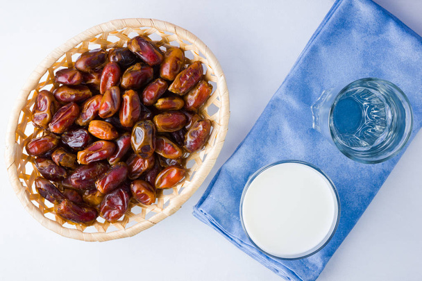 Dried dates and milk on white background. Holy month of Ramadan, concept. Righteous Muslim lifestyle. Starvation. Dates in wooden basket and water. Vegetarian food. Copy space - Foto, Bild