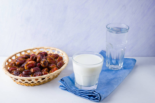 Dried dates and milk on white background. Holy month of Ramadan, concept. Righteous Muslim lifestyle. Starvation. Dates in wooden basket and water. Vegetarian food. Copy space - Foto, immagini