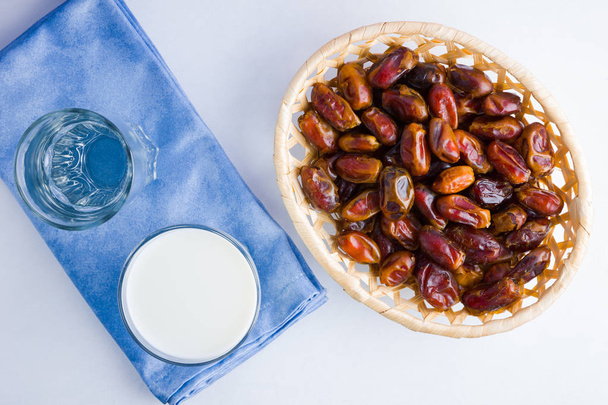 Dried dates and milk on white background. Holy month of Ramadan, concept. Righteous Muslim lifestyle. Starvation. Dates in wooden basket and water. Vegetarian food. Copy space - Fotografie, Obrázek