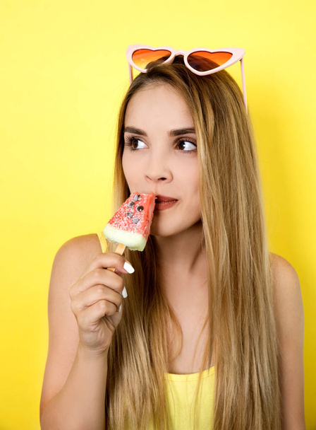 Young woman posing with ice cream on yellow background - Фото, изображение