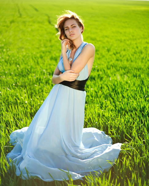 A young woman in a long blue dress enjoying a sunny day - Φωτογραφία, εικόνα