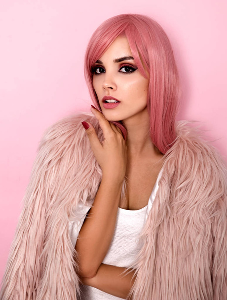 Portrait of young woman in fur coat and pink wig - 写真・画像