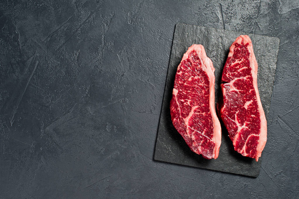Raw beef ramp steak. Black background, top view. - Valokuva, kuva