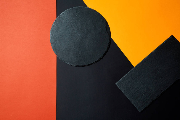 From above of empty black slate serving board on multicolored background with geometric composition - Fotoğraf, Görsel