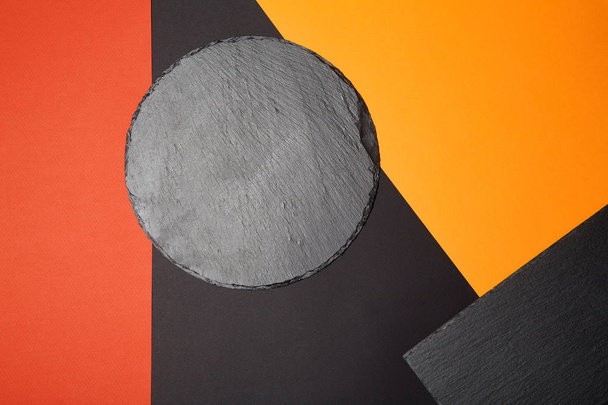 De cima de placa de serviço de ardósia preta vazia em fundo multicolorido com composição geométrica
 - Foto, Imagem