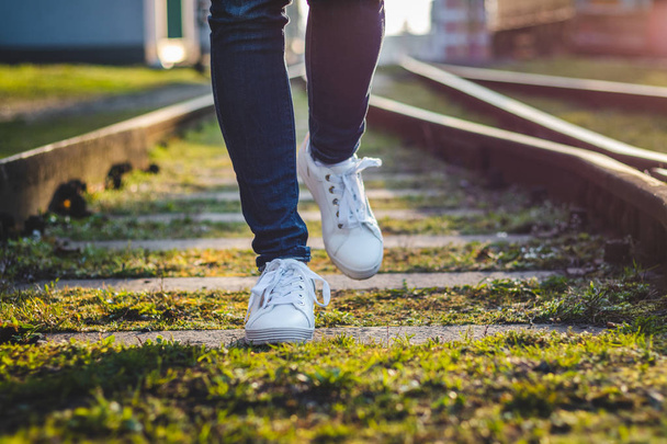 Жінка в білих кросівках біжить на залізничній колії. Жіночі ноги зі спортивним взуттям. Вправа на відкритому повітрі
. - Фото, зображення