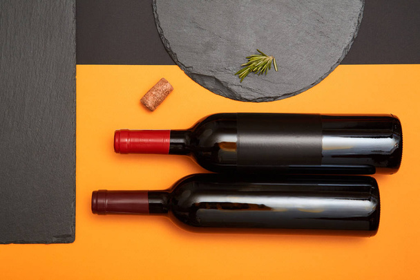 Renkli geometri arka plan üzerinde şarap şişesi ile siyah kayrak tahtası düzeni - Fotoğraf, Görsel