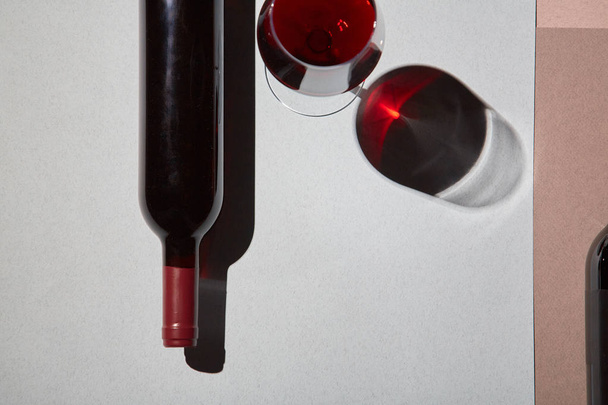 Layout of bottles and glass of red wine on colorful paper background - Photo, Image