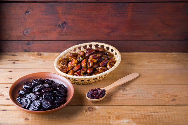 Dried dates and prunes on wooden background. Holy month of Ramadan, concept. Righteous Muslim lifestyle. Starvation. Dried fruits: dates, prunes and raisins on wooden boards - Fotoğraf, Görsel