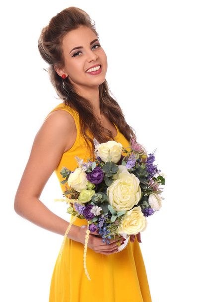 Beautiful young girl in a yellow dress with a bouquet of flowers - Фото, зображення
