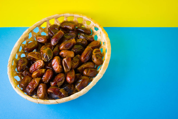 Dried dates on a yellow blue background. Holy month of Ramadan, concept. Righteous Muslim lifestyle. Starvation. Dates in a wooden basket in the style of minimalism - Foto, Bild