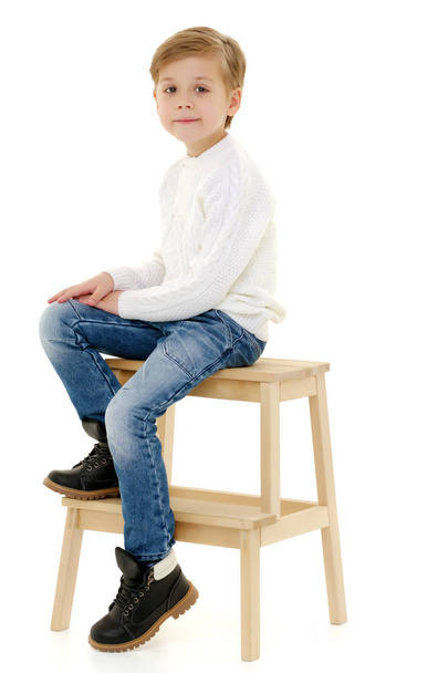 A little boy is sitting on a chair. - 写真・画像
