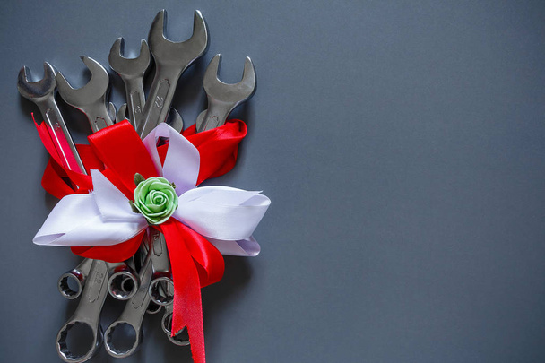 A set of tools of wrenches for repair on a gray background in festive packing bouquets copy space of a flat view from above, concept of a gift for the father's day - Foto, afbeelding