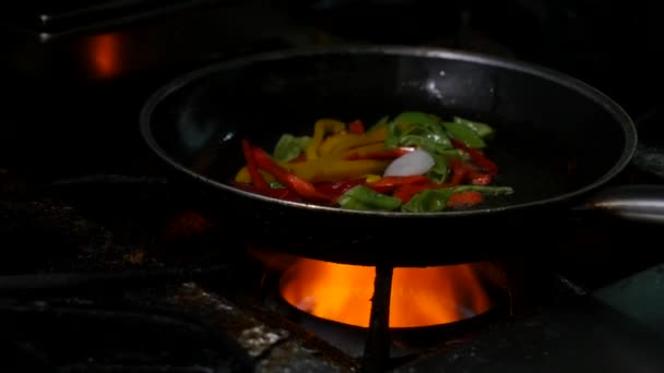Professionele chef-kok en vuur. Groenten en eten koken boven een open vuur op een donkere achtergrond - Video